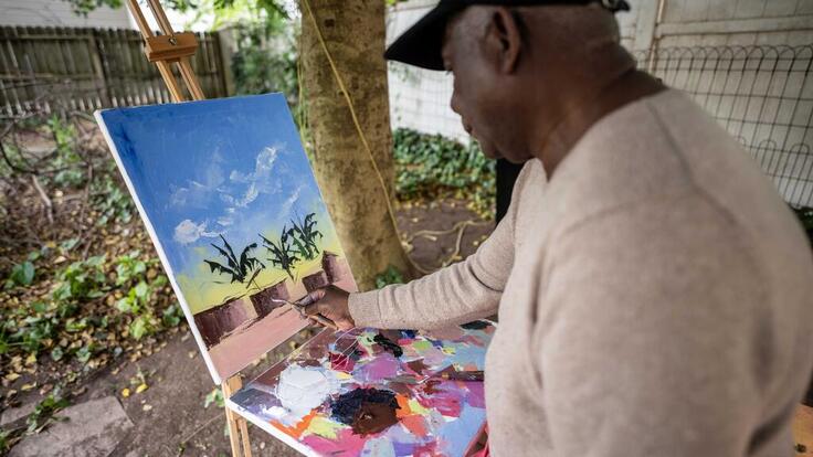 Chishimba is painting a colourful landscape.
