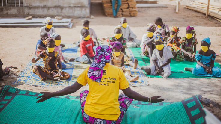 IRC teach sits in front of her class of young pupils who are wearing masks and socially distancing.