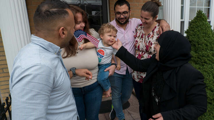 Maha al-Obaidi, a refugee from Iraq, interacts with her grandson in his mother's arms.