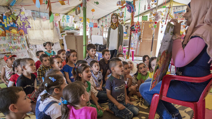 Children huddled together listening to educational stories.